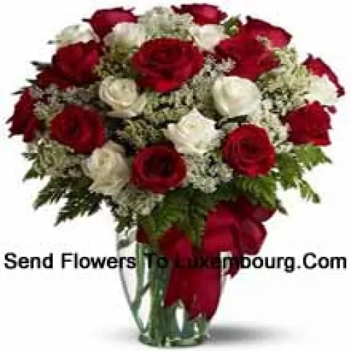 15 Red And 10 White Roses With Some Ferns In A Glass Vase